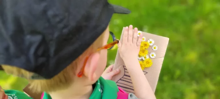 photo d'un petit garçon à lunettes regardant une carte postale avec des fleurs